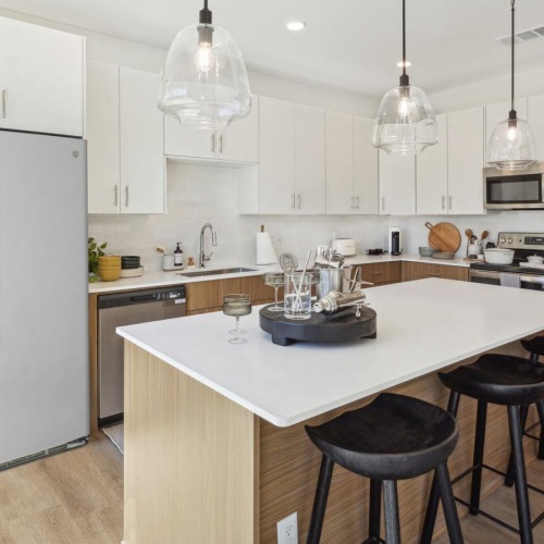 Beautiful kitchens with designer finishes a kitchen with white cabinets and pendant lighting above island