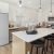 a kitchen with white cabinets and pendant lighting above island